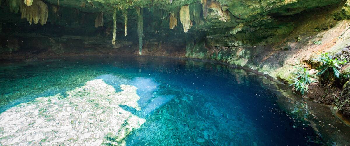 A cave with clear blue water and stalactites.