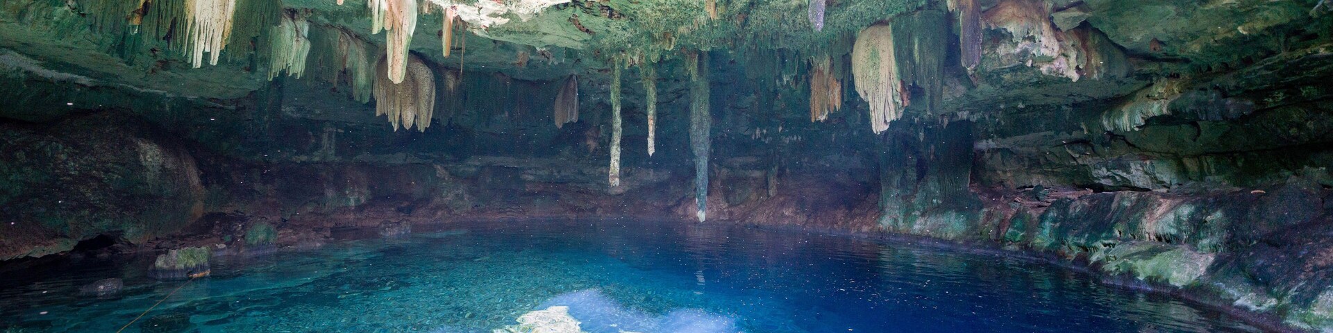 Caverna com águas azul-claras e estalactites.