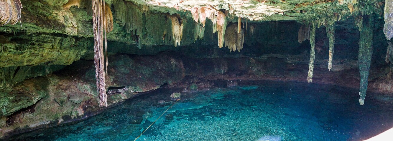 Una cueva con estalactitas y una piscina azul cristalina.