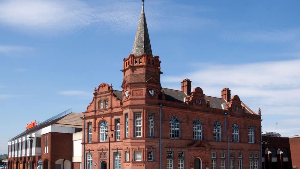 Un grand bâtiment en briques rouges, doté d’une haute tour et d’une horloge.