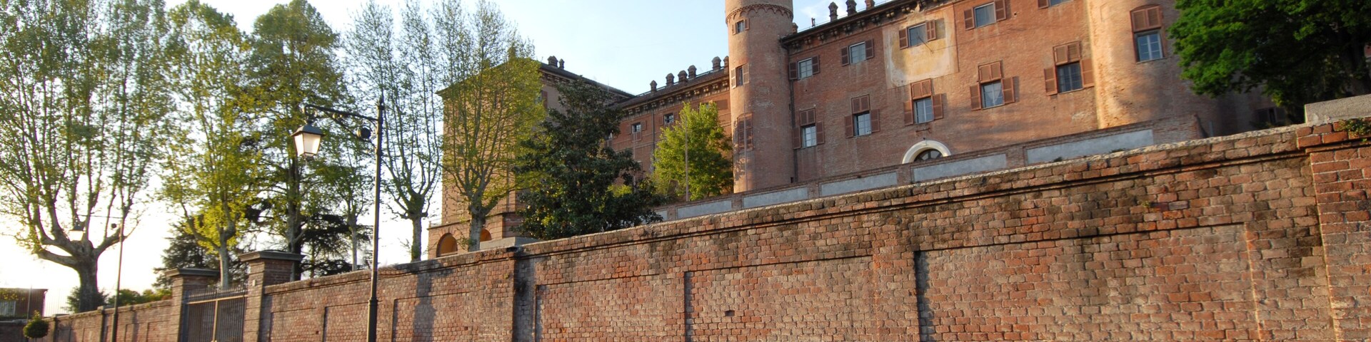 Um muro de tijolos histórico com duas torres e um edifício ao fundo.