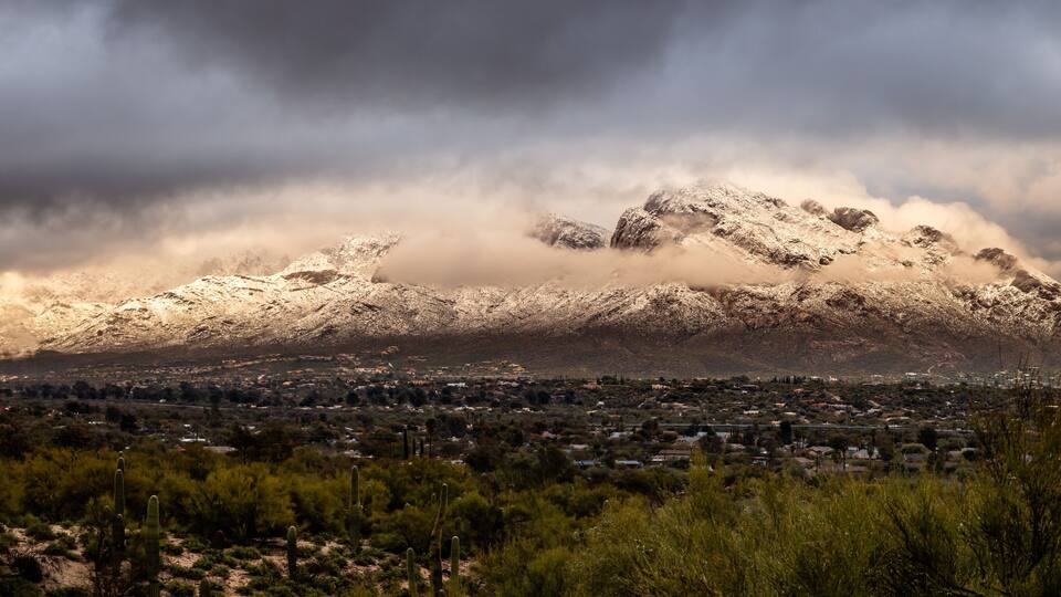A snow-capped mountain with a town in the foreground.