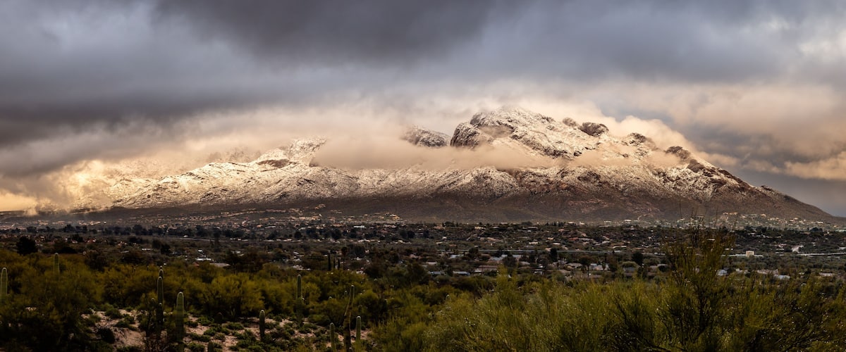 A snow-capped mountain with a town in the foreground.