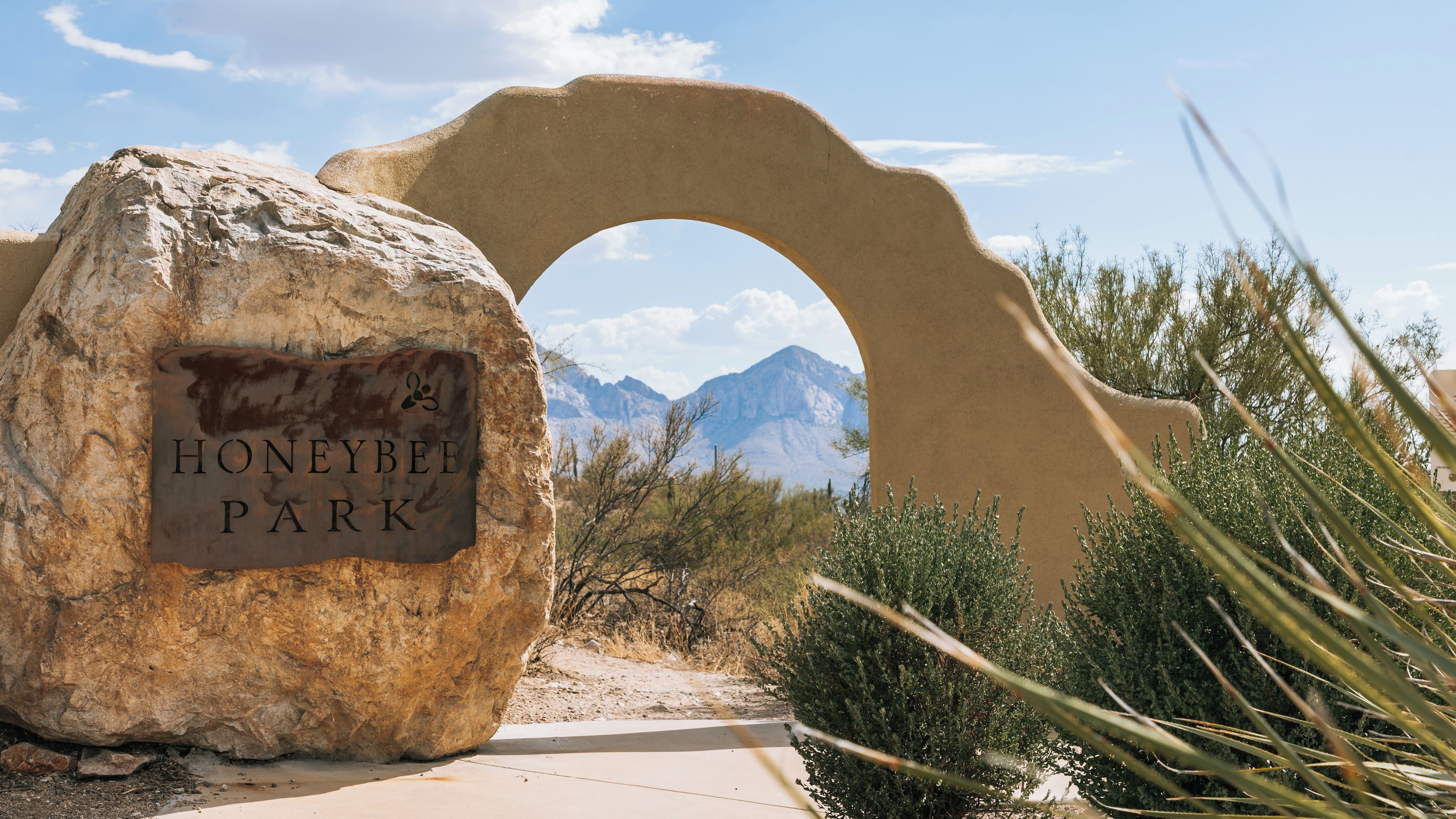 A large rock with a sign reading 'HoneybEE Park' and a natural archway.