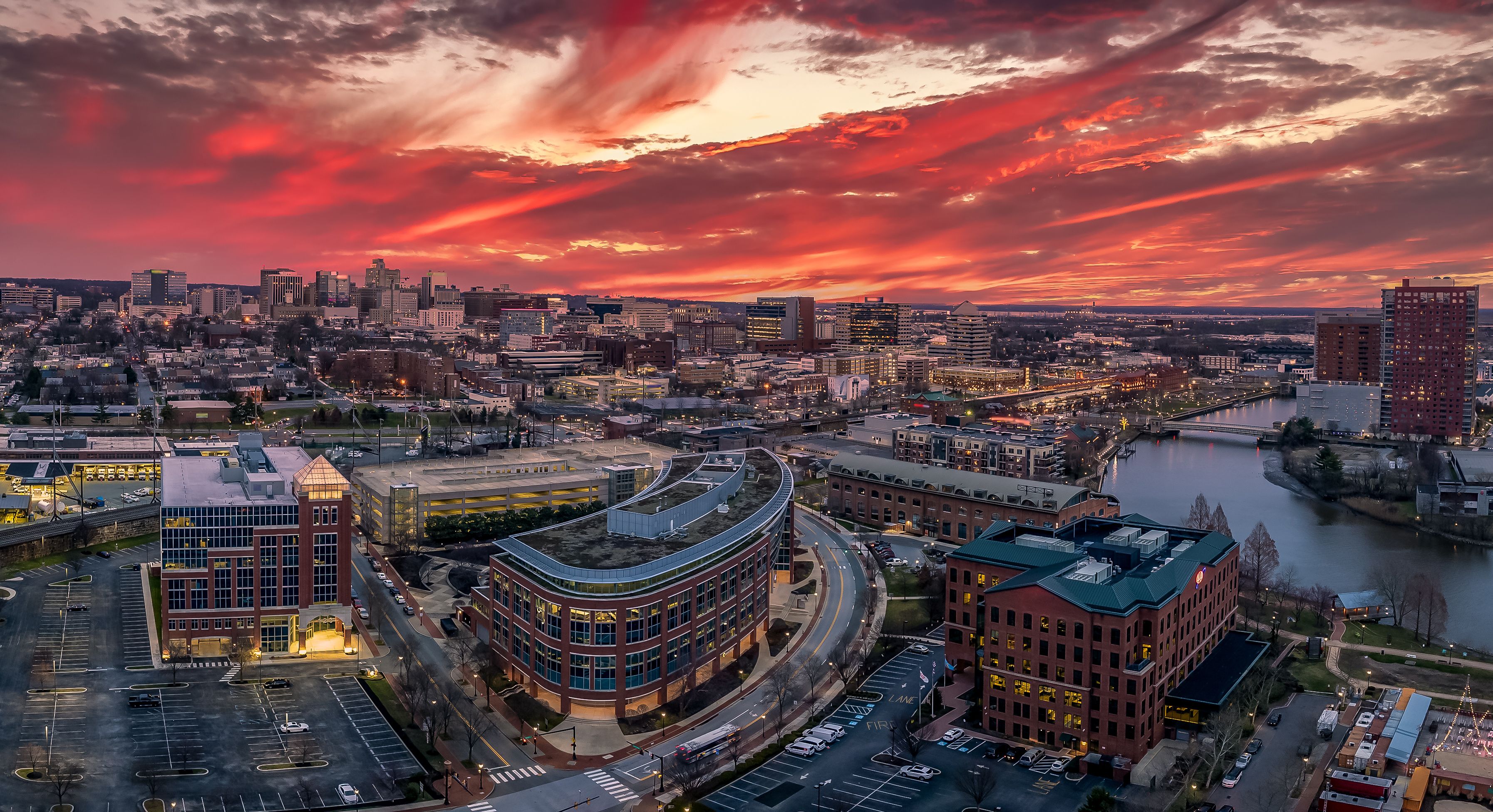 A cityscape at sunset with a river and modern buildings.