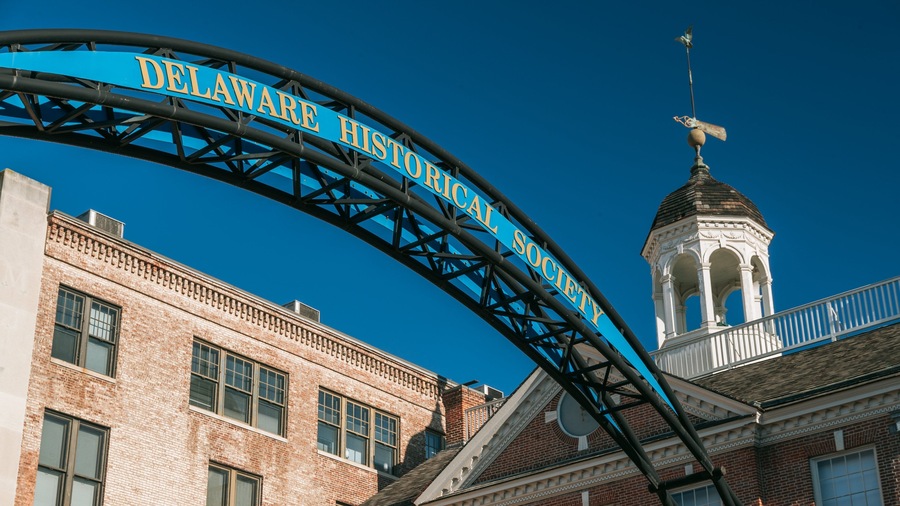Un arco azul con el texto "Delaware Historical Society" sobre un cielo azul despejado.