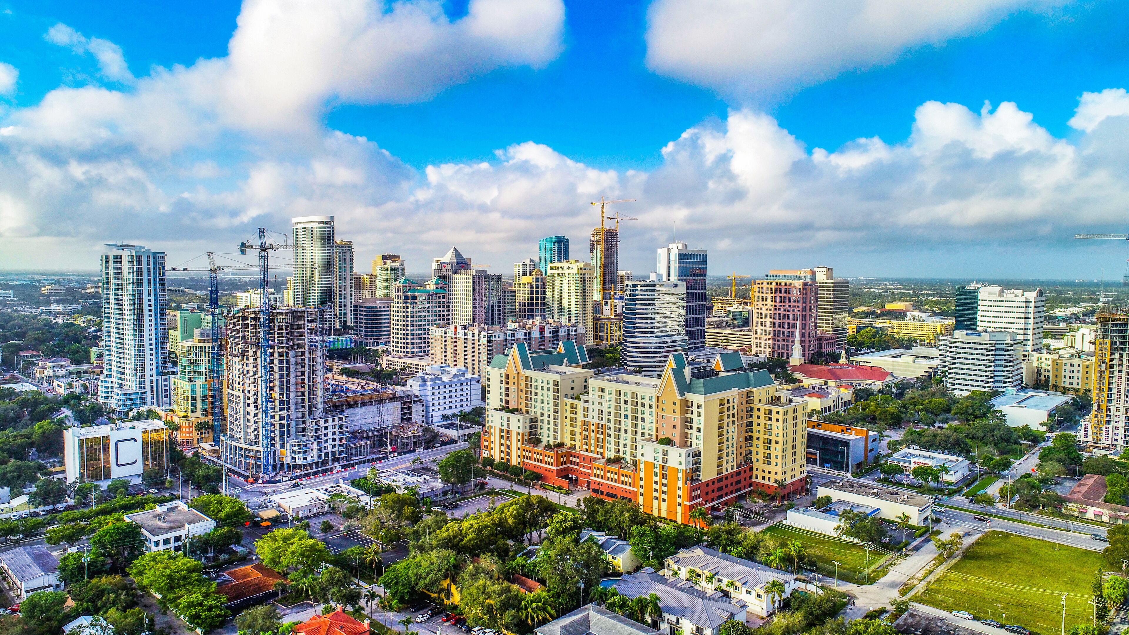 A cityscape with modern high-rise buildings, construction cranes, and a mix of residential and commercial structures.