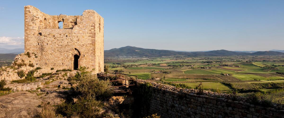 An ancient stone tower with a view of rolling hills and fields in the background.