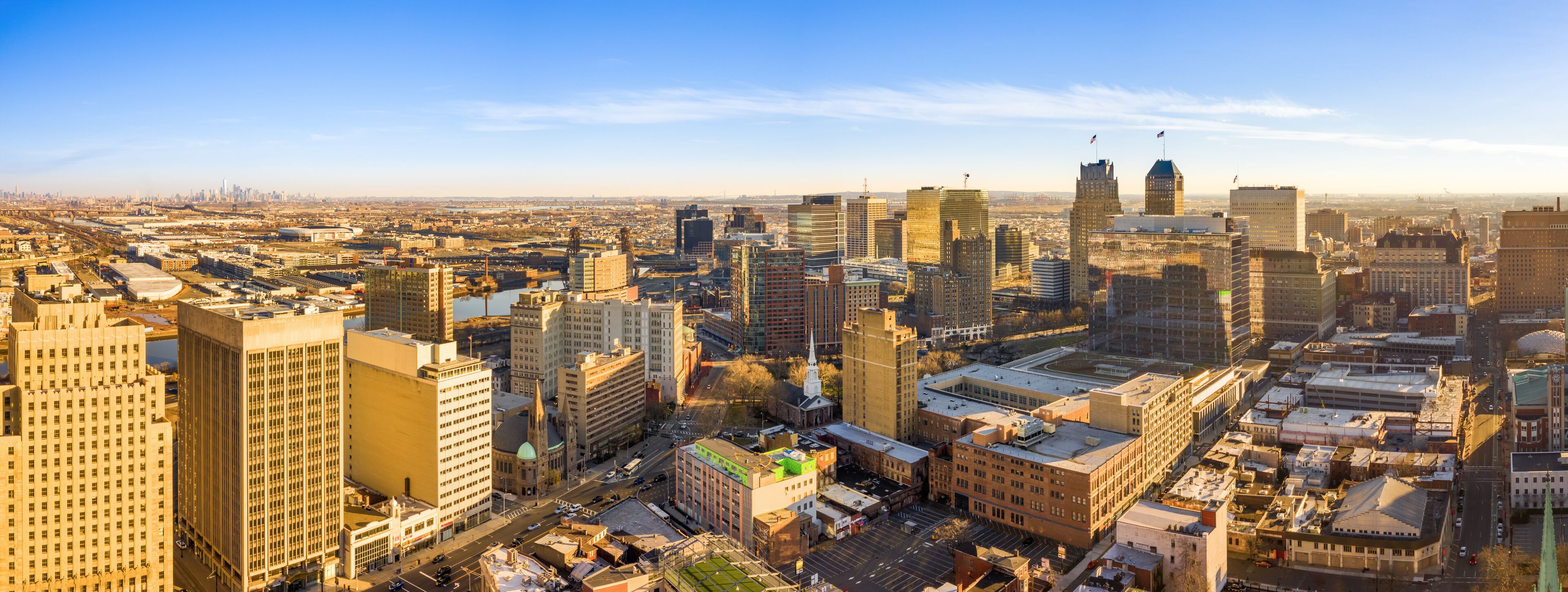 A cityscape with a mix of modern and historic buildings, a river, and a clear sky.