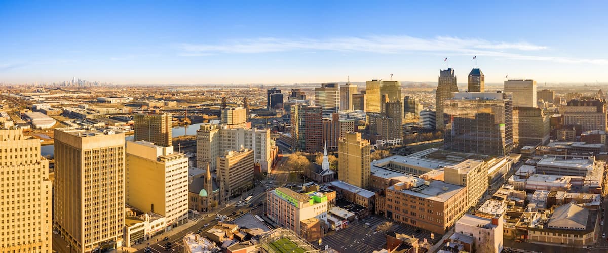 A cityscape with a mix of modern and historic buildings, a river, and a clear sky.