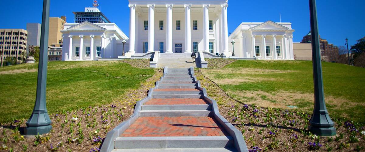 A grand white building with columns, a central staircase, and a clear blue sky.