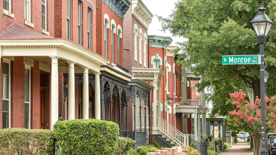 A row of red brick townhouses with white trim and green street signs at Monroe St.