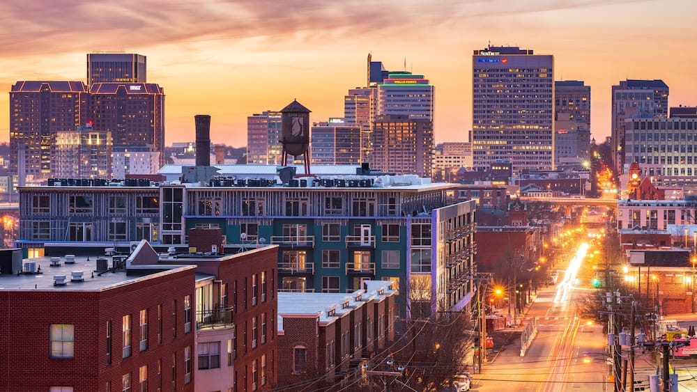 A cityscape with a sunset sky, tall buildings, and a busy street with light trails.