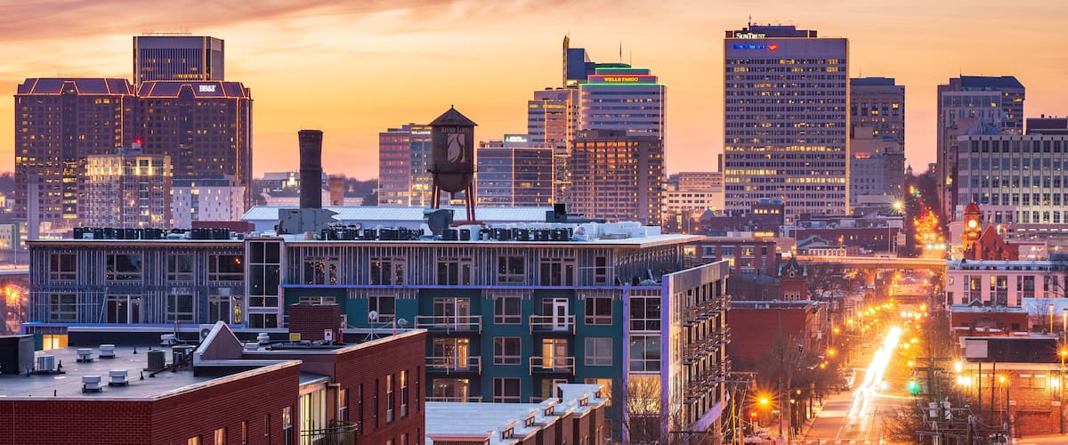 A cityscape with a sunset sky, tall buildings, and a busy street with light trails.