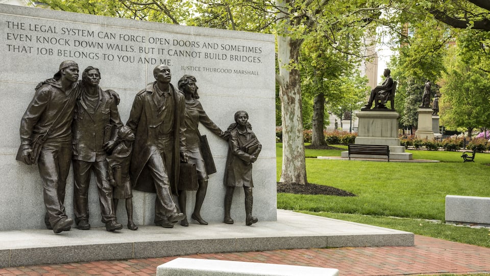 A statue of four figures with a plaque.