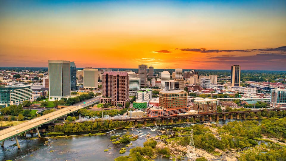 A cityscape with a river, a bridge, and a sunset.