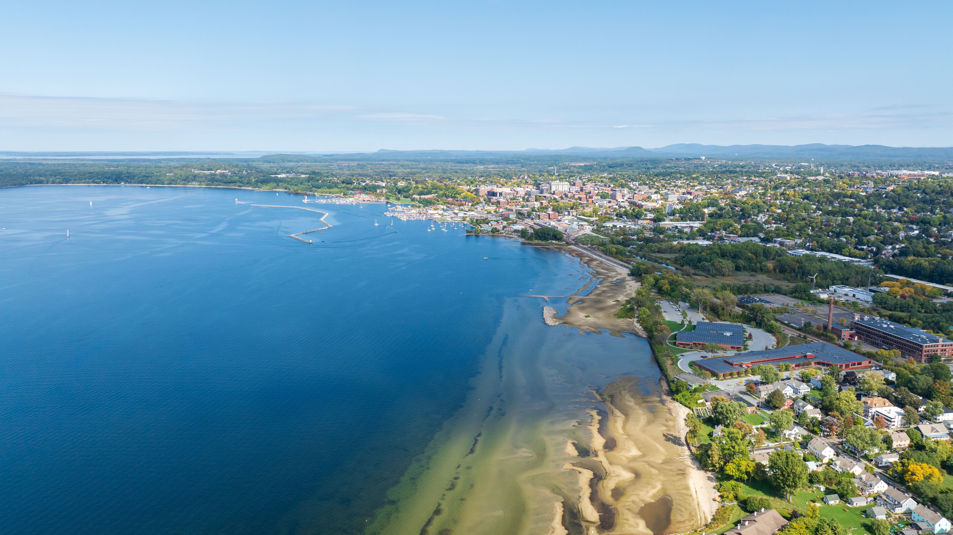 Aerial view of Burlington, Vermont with Lake Champlain's blue waters and marina stretching into the distance.