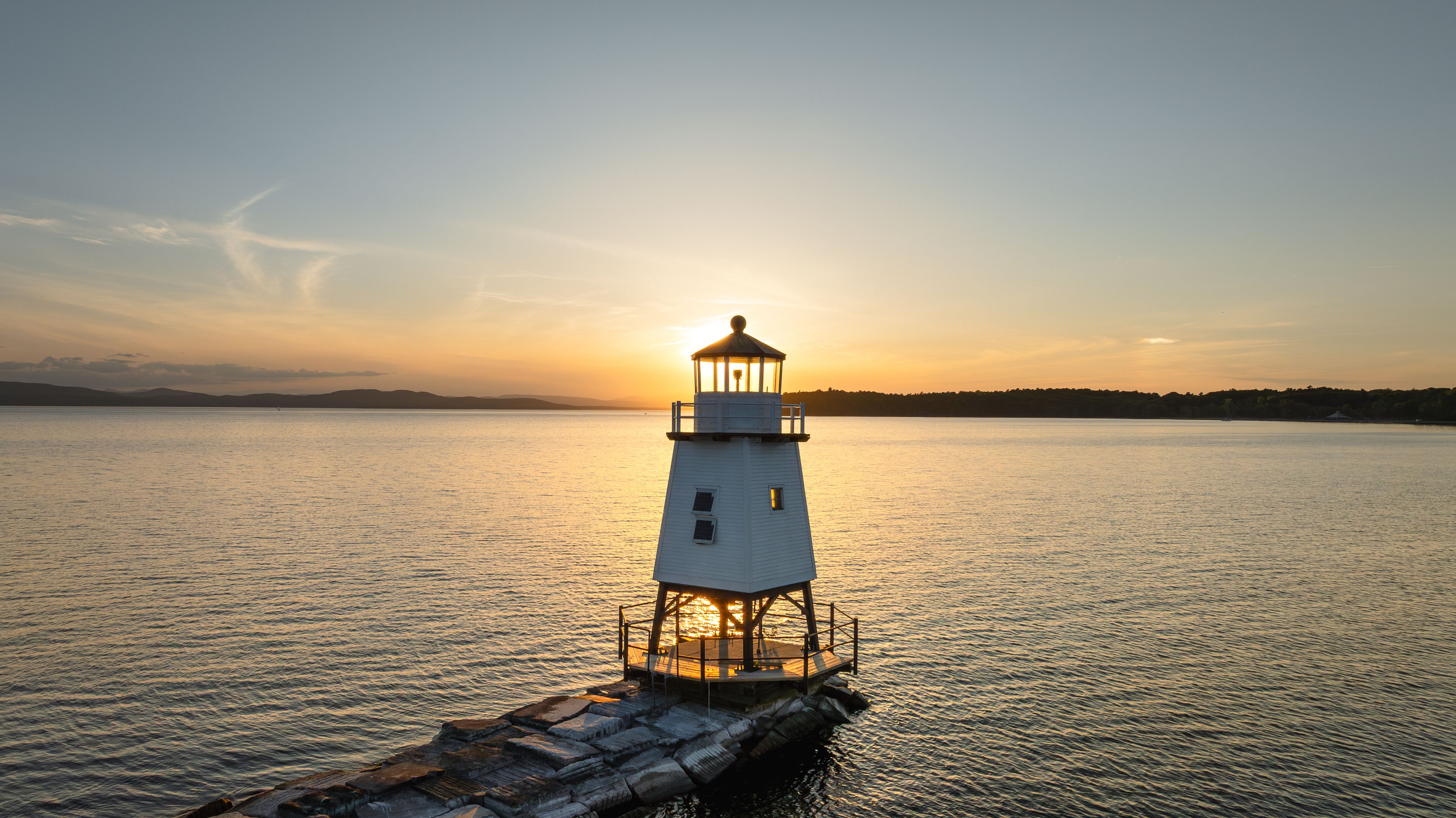 A lighthouse on a pier at sunset.