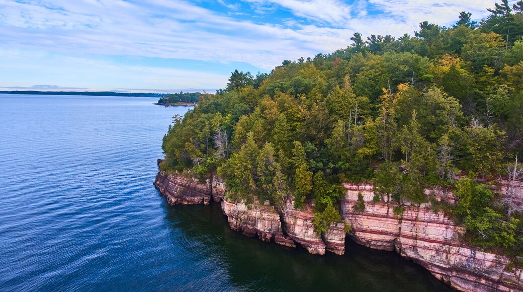 Aerial over cliffs on Vermont coast with lush green forest above