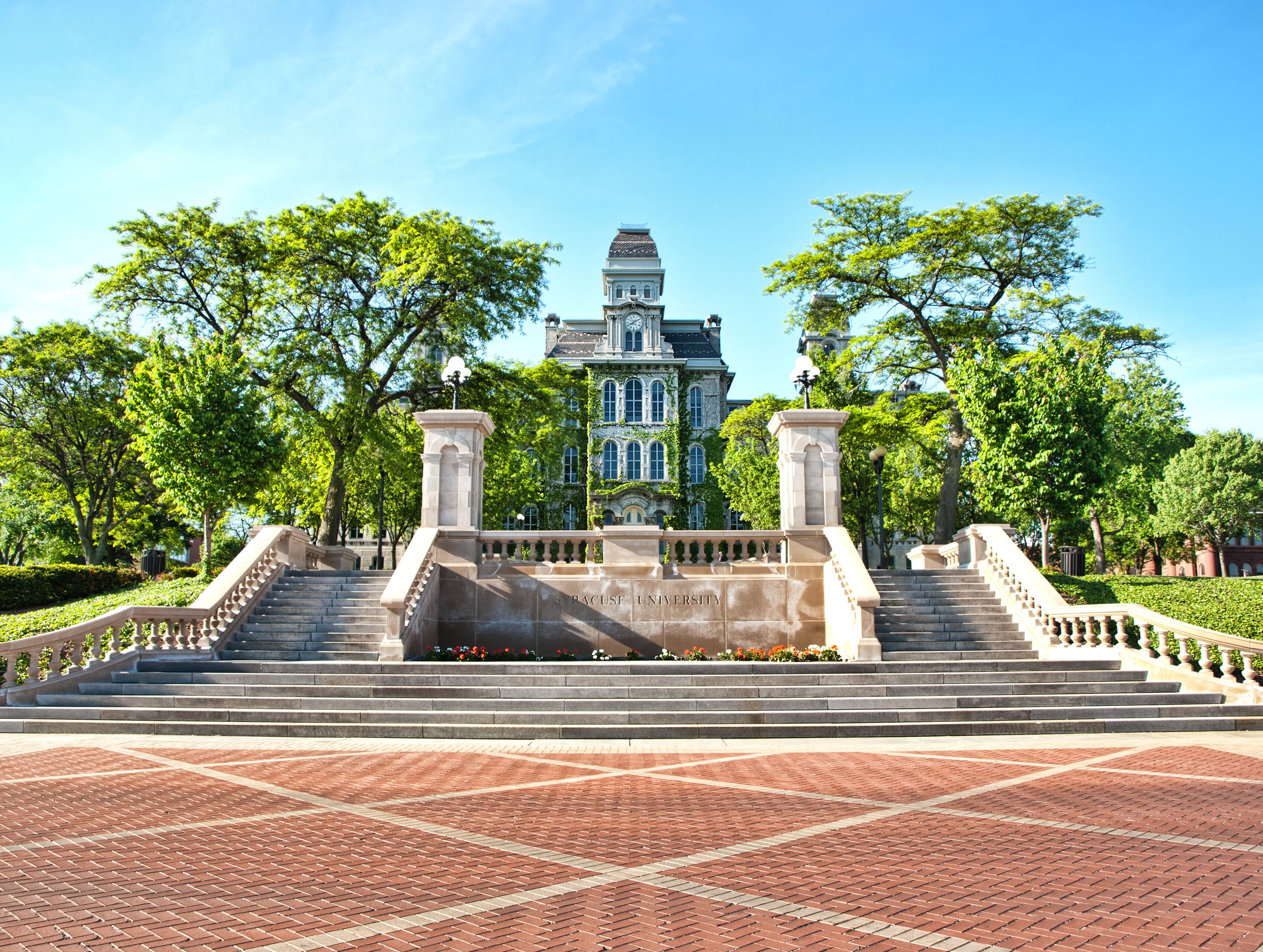 A historic building with a central staircase and a brick plaza.