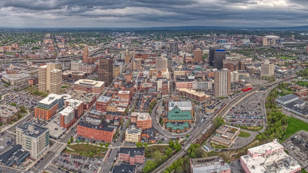 A cityscape with a mix of historic and modern buildings, a large green park, and a prominent stadium.