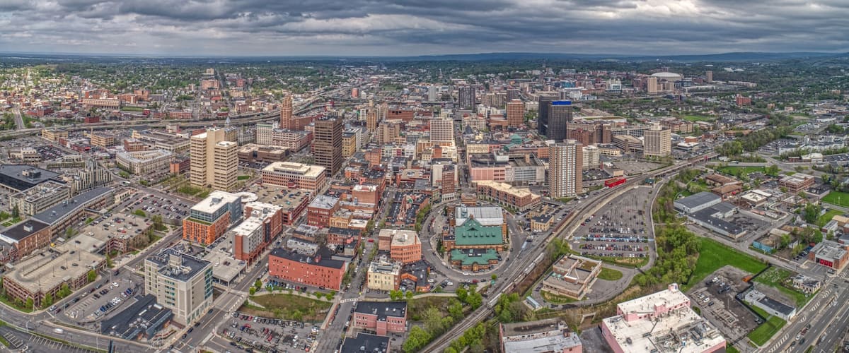 A cityscape with a mix of historic and modern buildings, a large green park, and a prominent stadium.