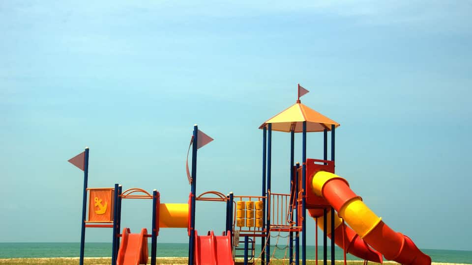 A colorful playground with slides and climbing structures near the beach.