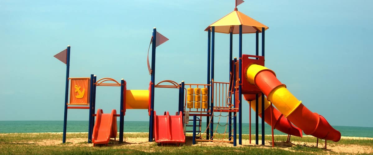 A colorful playground with slides and climbing structures near the beach.