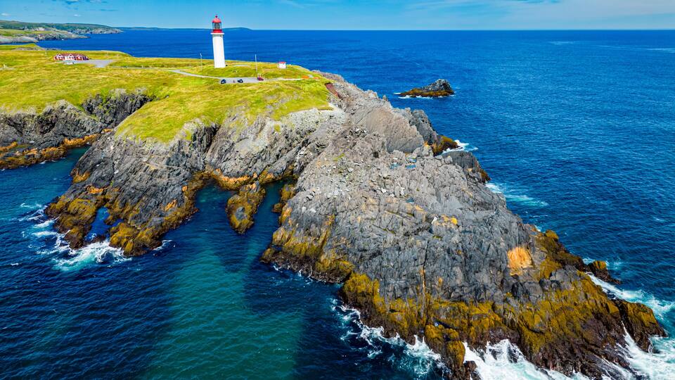 A lighthouse on a rocky coastline with clear blue waters.