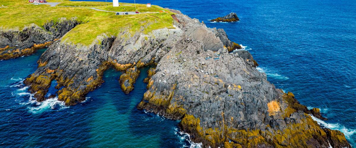 A lighthouse on a rocky coastline with clear blue waters.