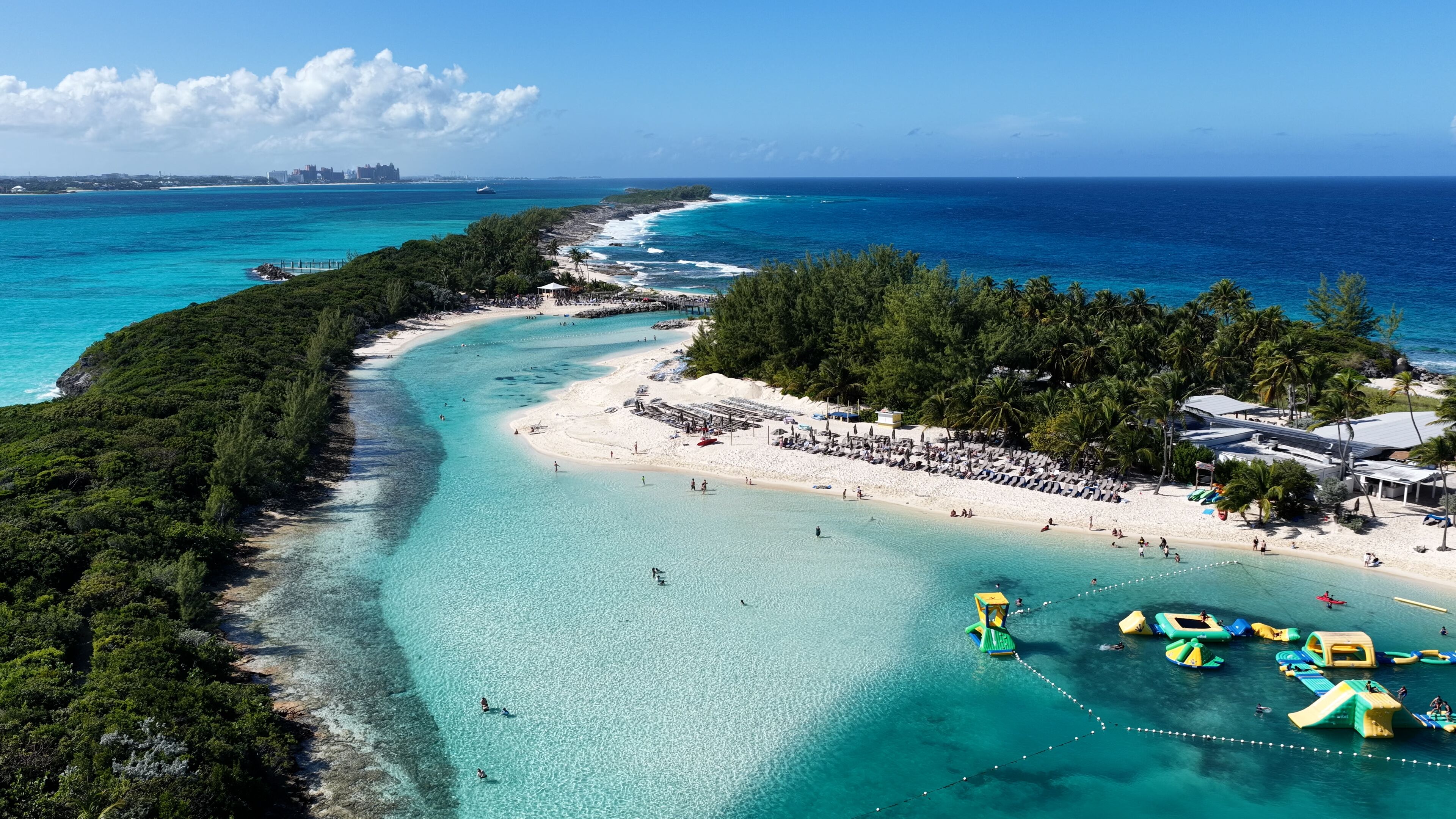 Uma praia tropical com águas turquesa cristalinas, areal arenoso e vegetação exuberante.