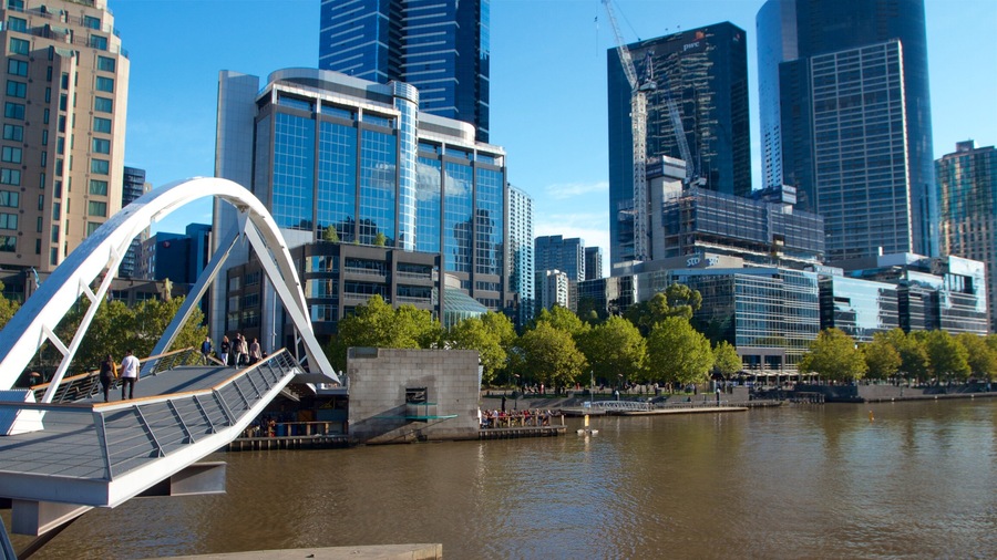 A modern cityscape with a river, a bridge, and several high-rise buildings.