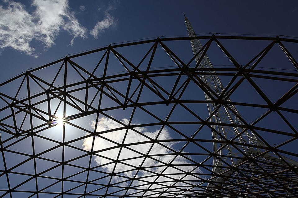 A large metal framework with the sun shining through the gaps.