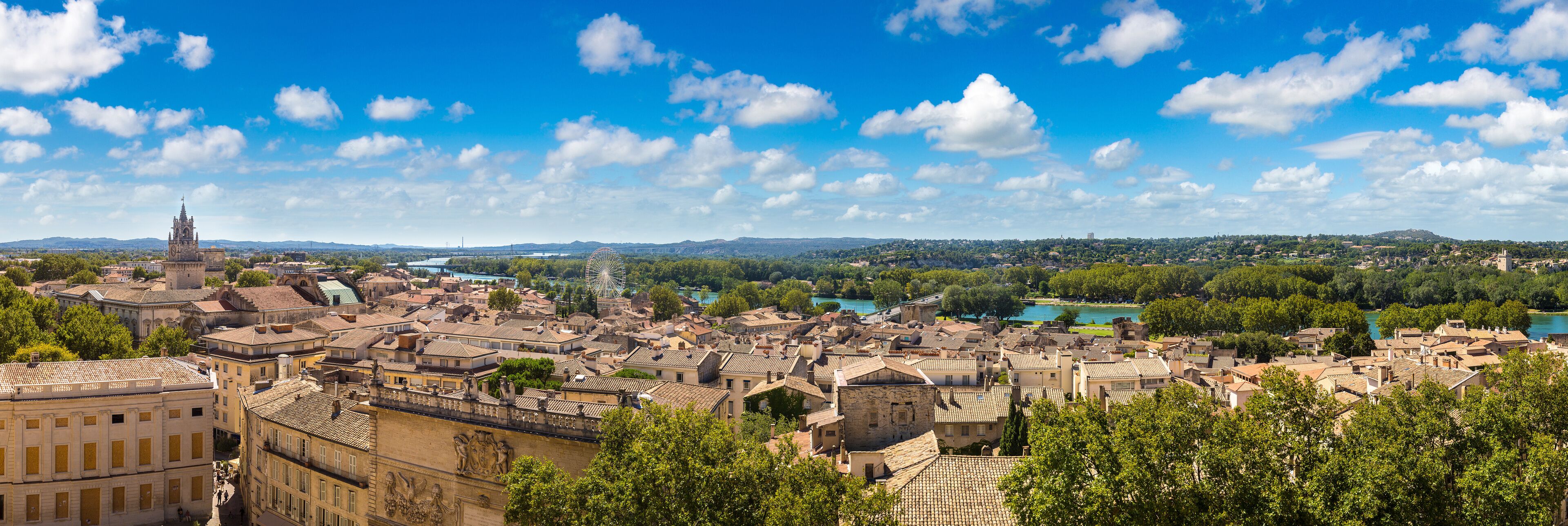 A historic town with a prominent church, a river, and a Ferris wheel in the distance.