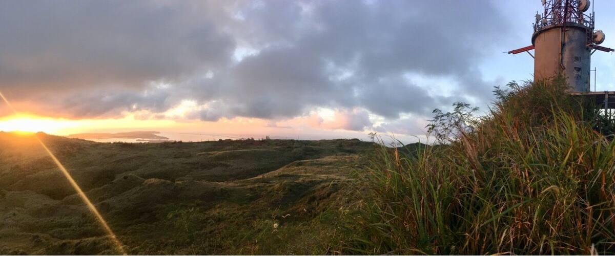 A sunset over a hilly landscape with a distant tower.