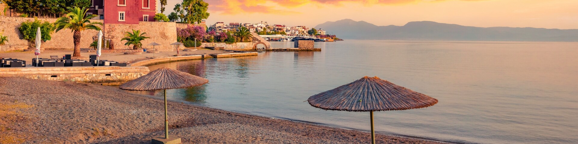Una playa con sombrillas, un edificio y un mar tranquilo.