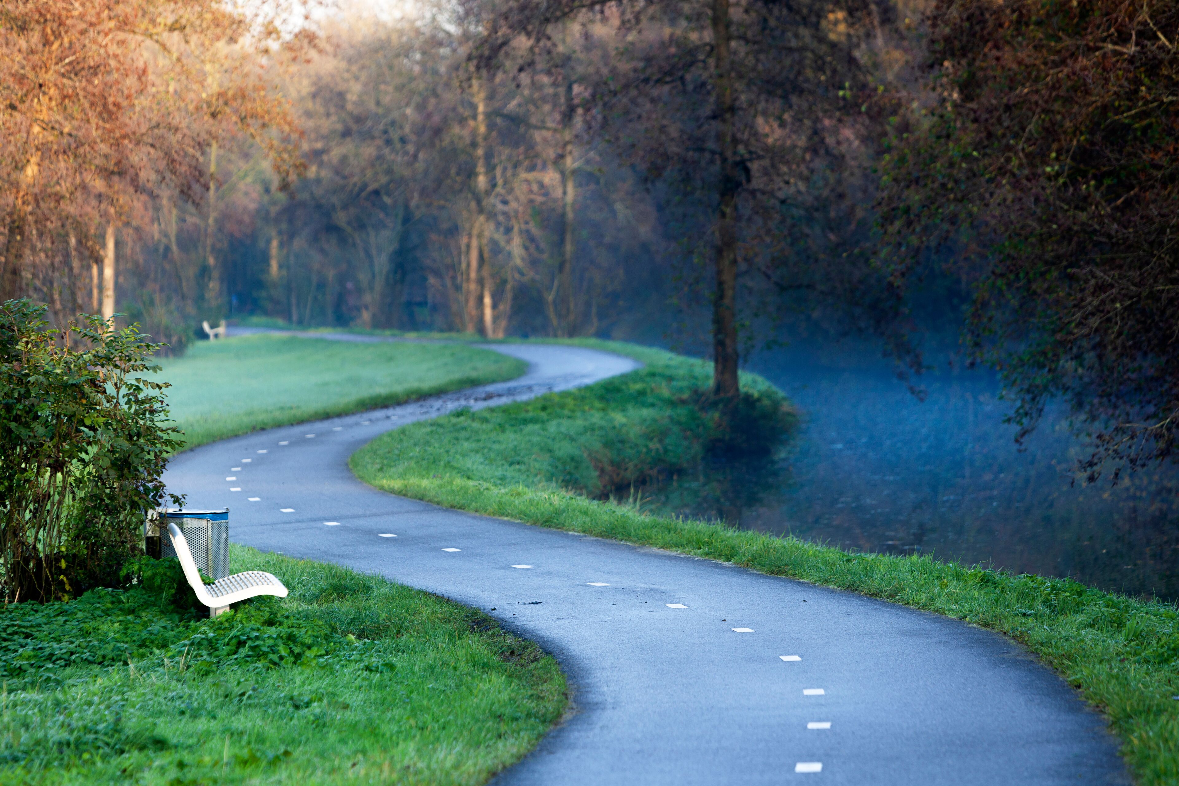 Winding two way bicycle path along a small river in autumn