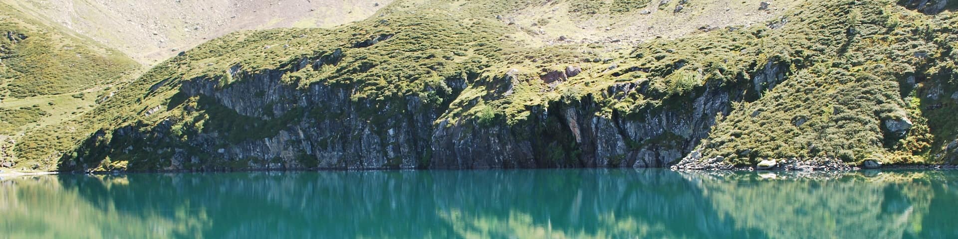 A mountain lake surrounded by rugged terrain and sparse vegetation.