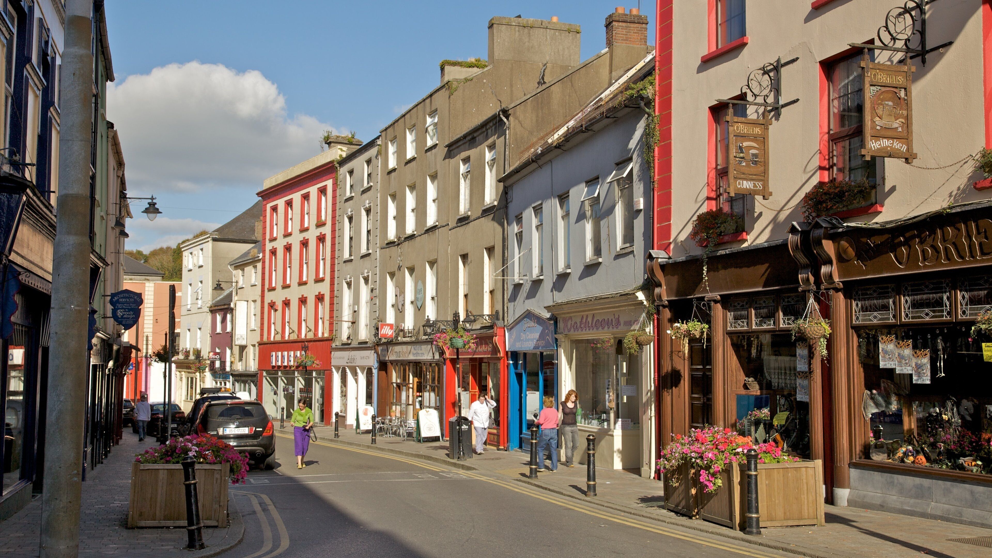 A street lined with colorful buildings, including a pub with a sign for O'Brien's and a store with a sign for Kathleen's.