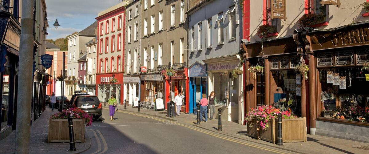 A street lined with colorful buildings, including a pub with a sign for O'Brien's and a store with a sign for Kathleen's.