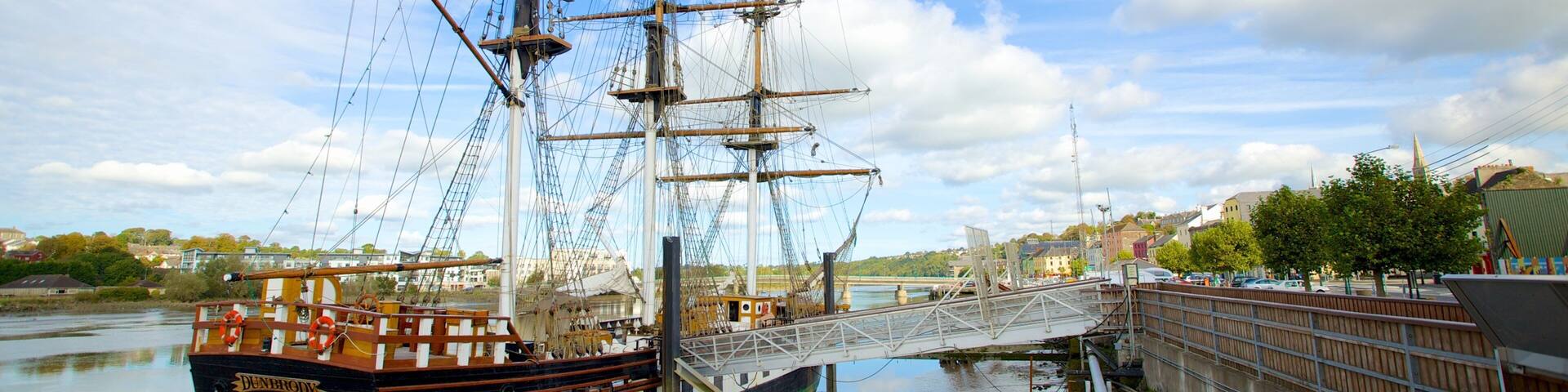 A tall ship docked at a pier with a bridge connecting to the dock.