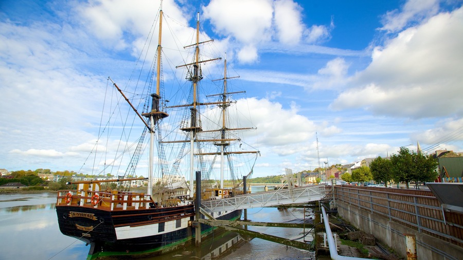 A tall ship docked at a pier with a bridge connecting to the dock.