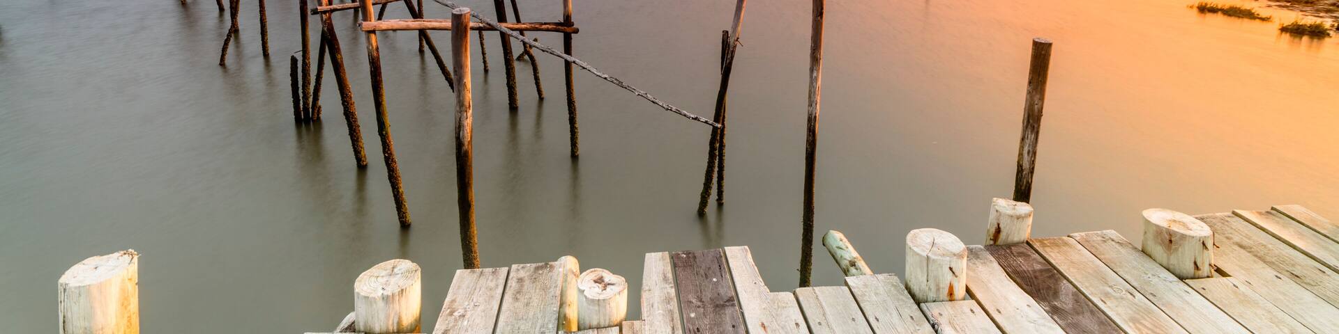 A wooden pier extending into calm waters at sunset.