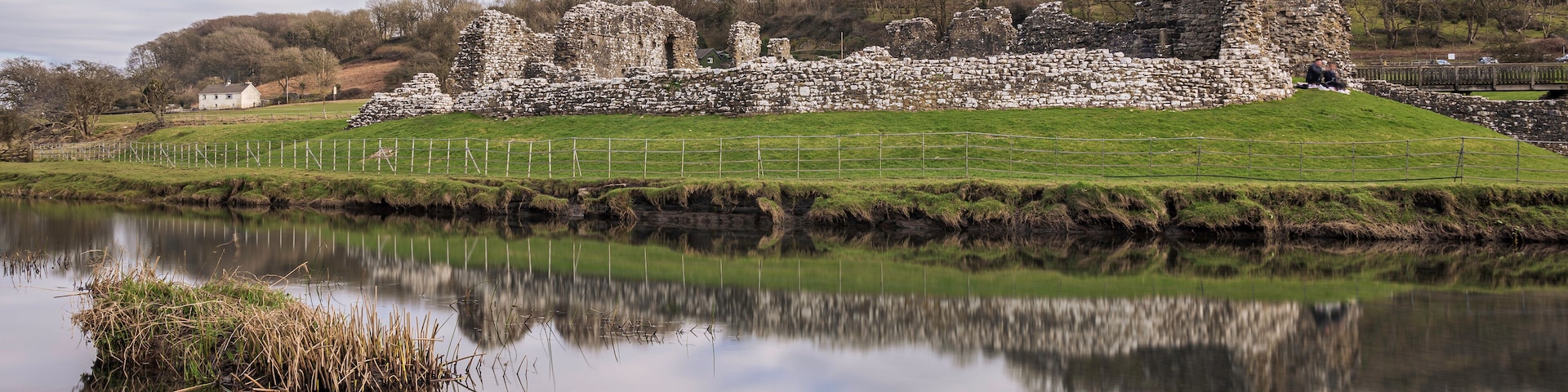 Ogmore Castle, A ruined Norman castle near Bridgend, south Wales. The castle is reflected on the smooth water of the river Ogmore.