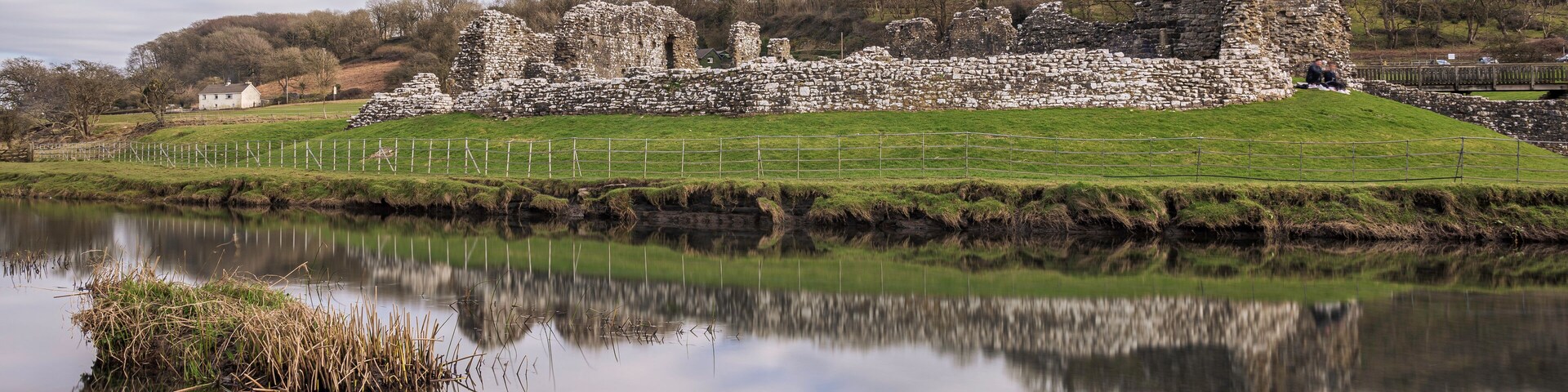 Ogmore Castle, A ruined Norman castle near Bridgend, south Wales. The castle is reflected on the smooth water of the river Ogmore.