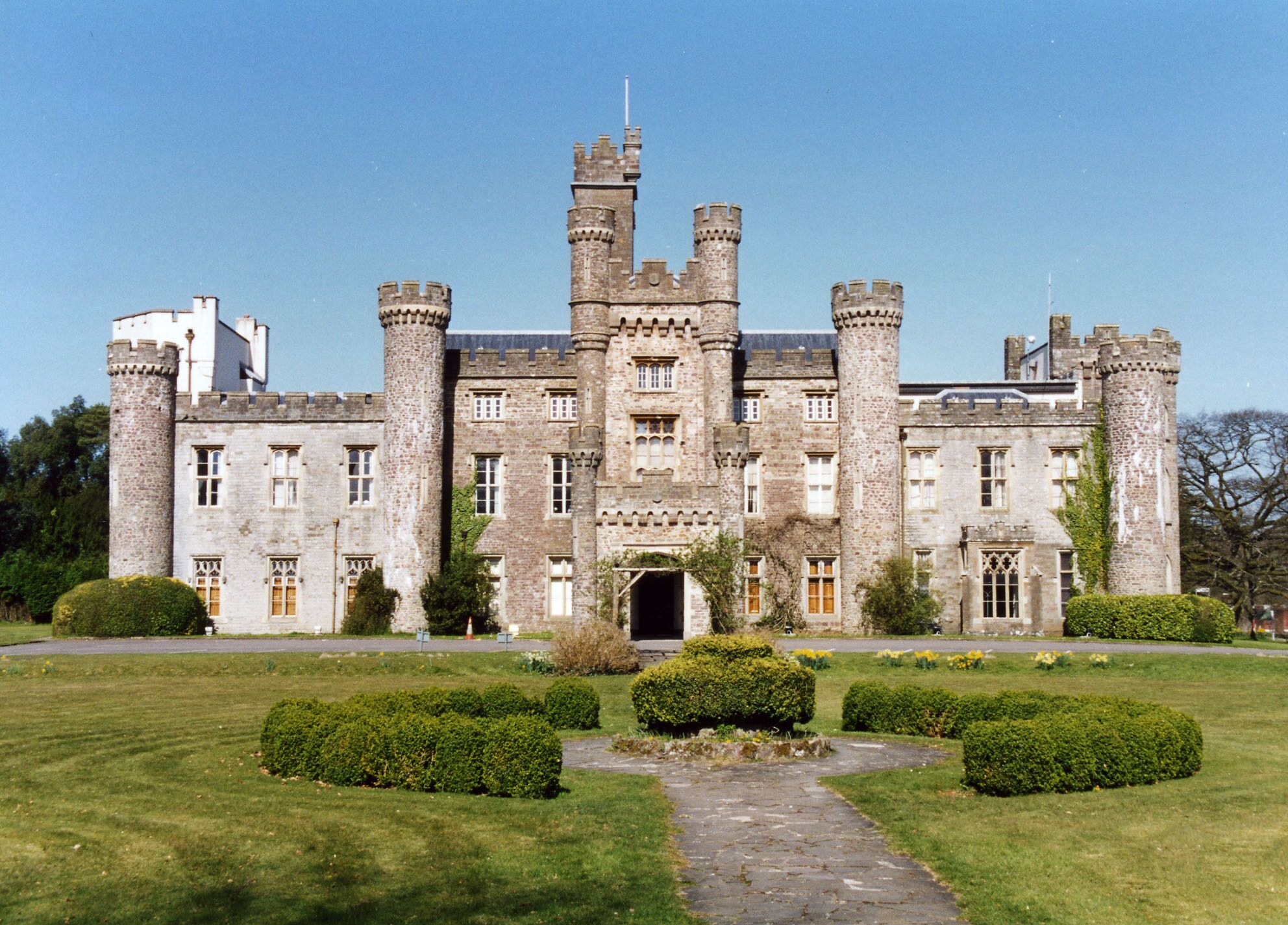 A large, historic castle with multiple towers and a well-maintained garden.