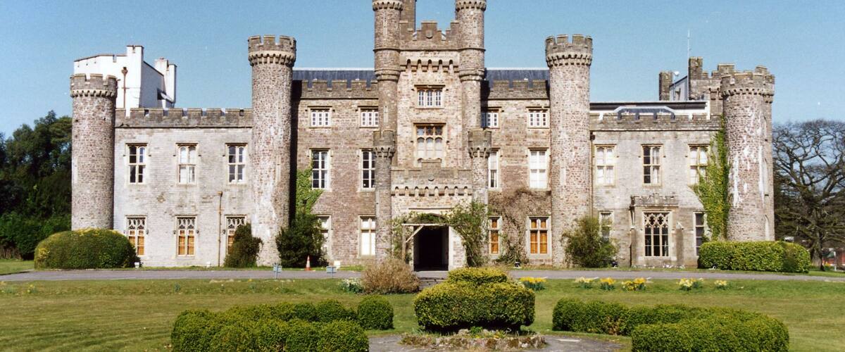 A large, historic castle with multiple towers and a well-maintained garden.