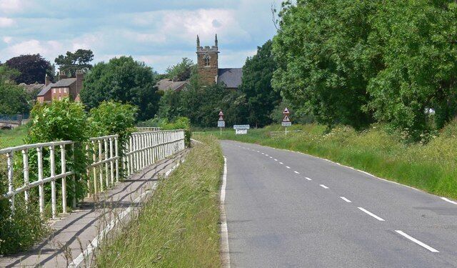 A rural road with a church tower in the background.