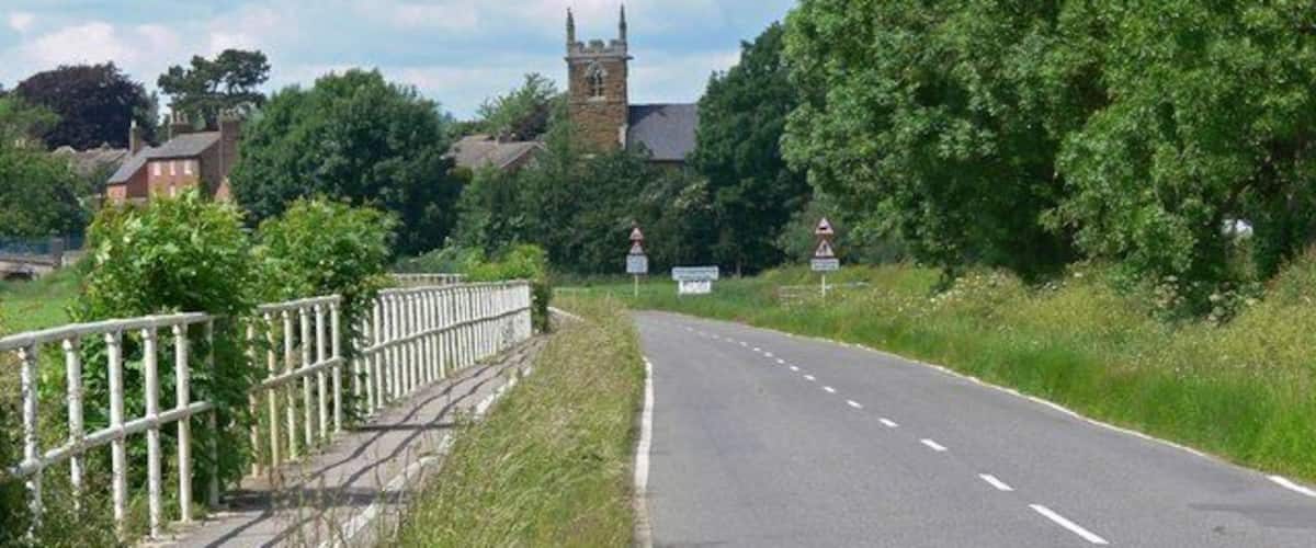A rural road with a church tower in the background.