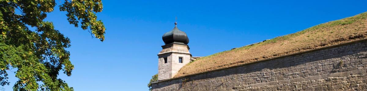 A stone wall with a watchtower, a clear sky, and a pathway leading to the wall.